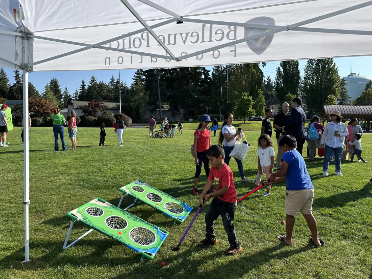 During the National Night event, children enjoy a fun ball-toss game under a tent in the park, fostering friendships and community relationships.