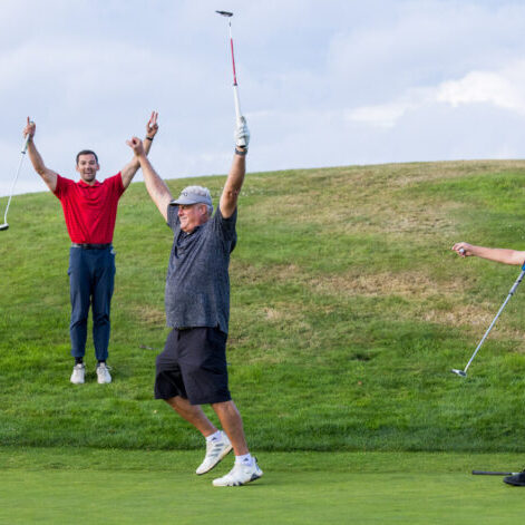 During the Golf Tournament, three people on the course celebrate a great shot; one raises arms in triumph, another in a red shirt joins the cheer, and the third in a blue cap points with his putter. Their joy echoes the success of this vital fundraising event for BPF.