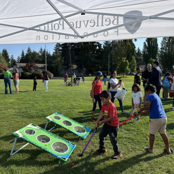 During the National Night event, children enjoy a fun ball-toss game under a tent in the park, fostering friendships and community relationships.